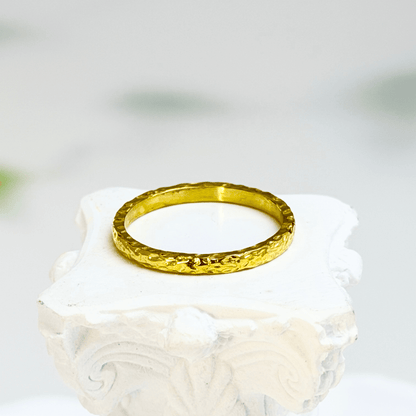 Minimal hammered slim gold ring with organic texture on a clean background.