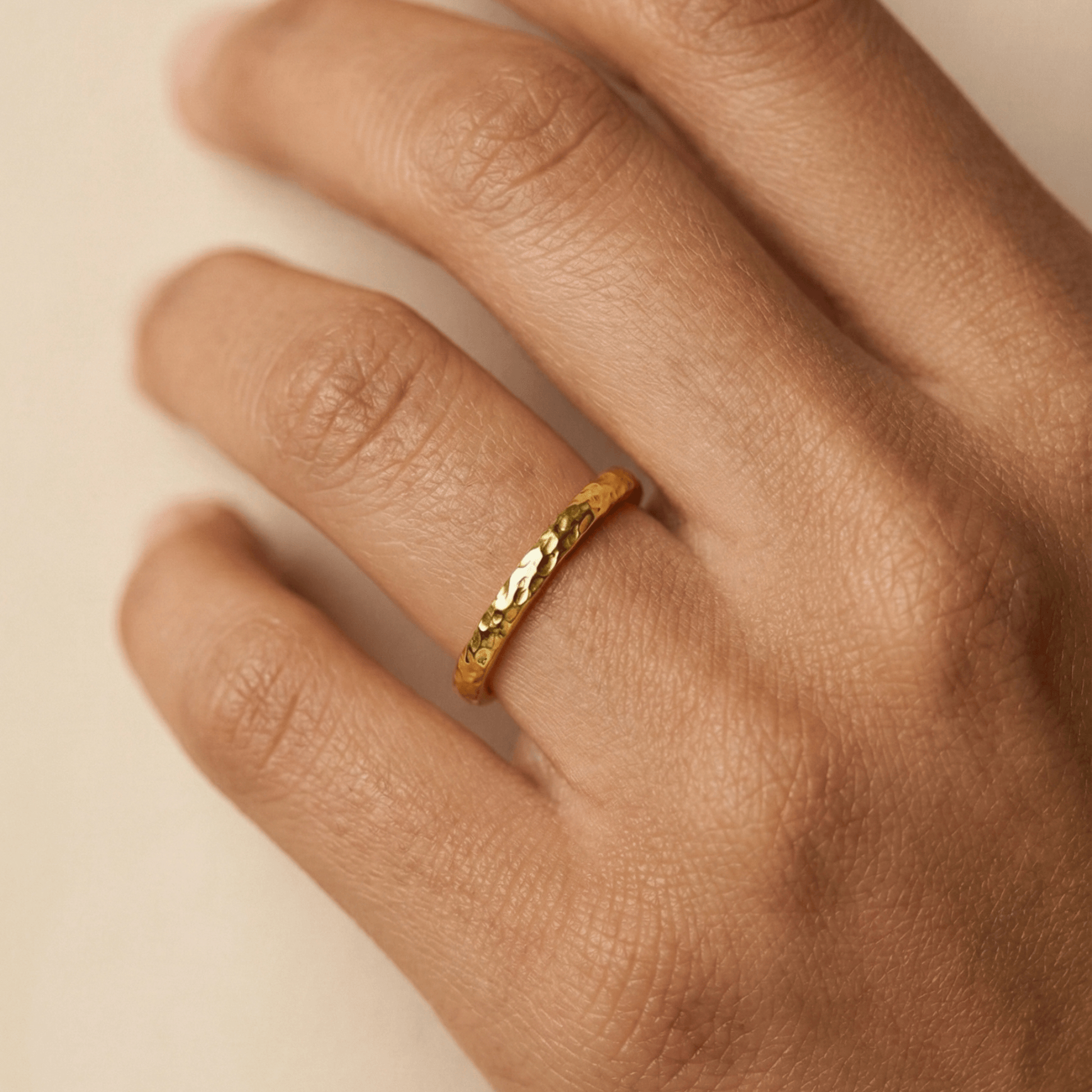 Minimal hammered slim gold ring with organic texture on a clean background.