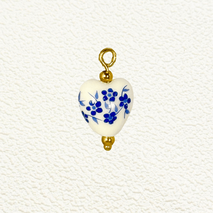Heart-shaped ceramic charm with small blue flowers and gold bead details