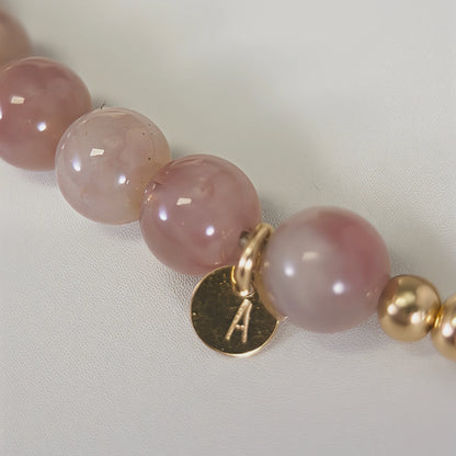 A beaded bracelet featuring mauve rose quartz, premium freshwater pearl, and stamped initial disc. 14k gold filled. MXW Jewellery