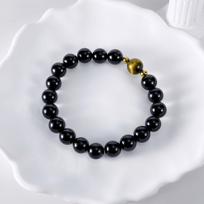 Men’s bracelet with polished black agate beads, single tiger’s eye gemstone, and gold accents on stretch cord.