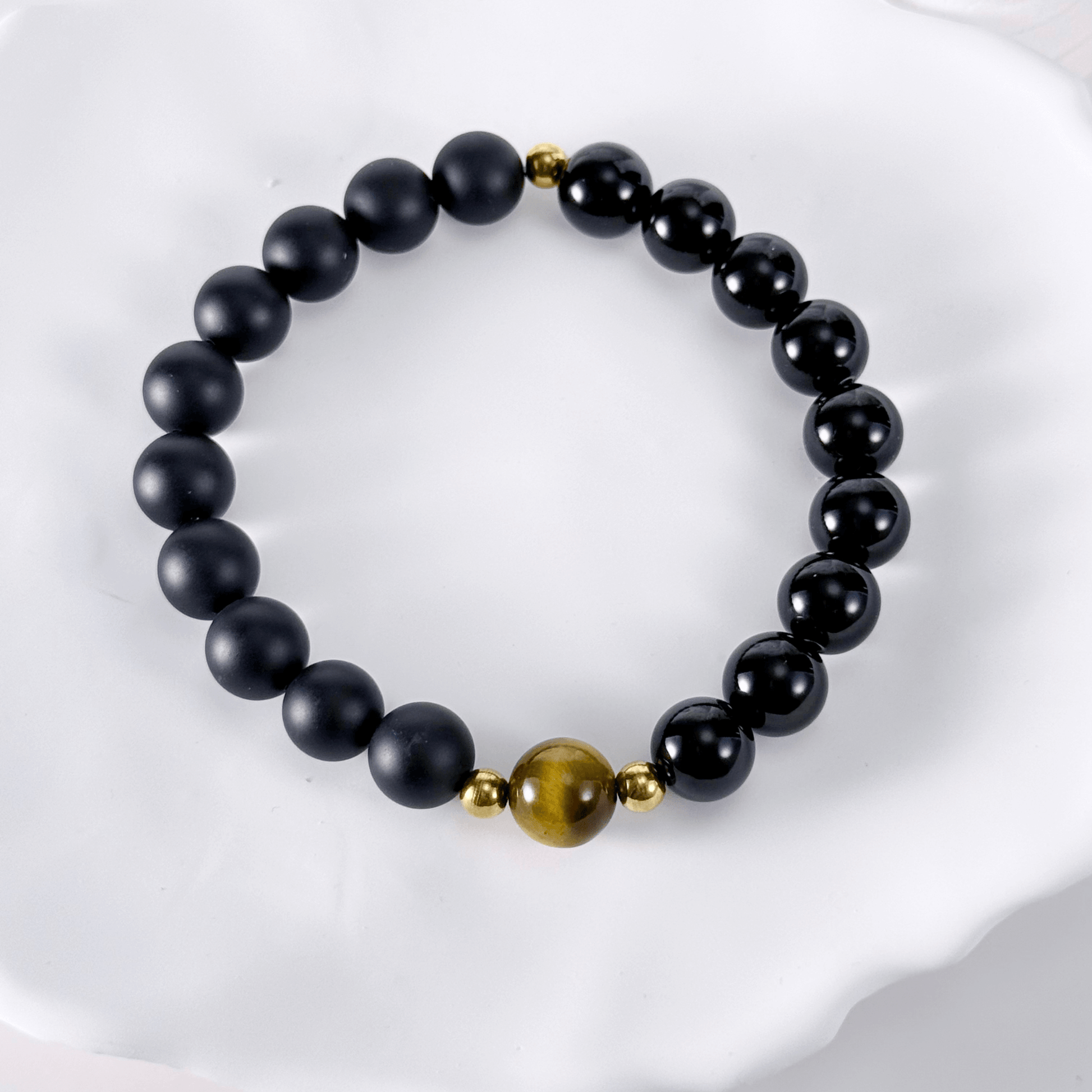 Men’s bracelet with polished black agate beads, single tiger’s eye gemstone, and gold accents on stretch cord.