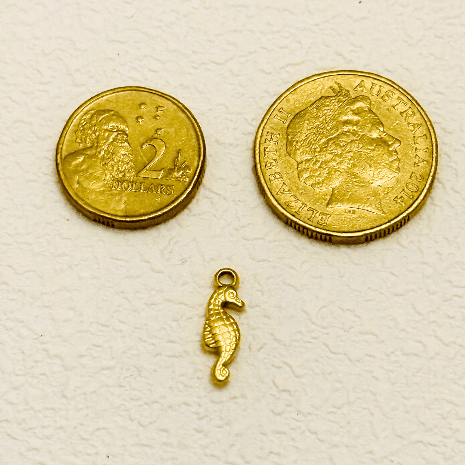 Gold seahorse charm with a textured diamond pattern and curved tail