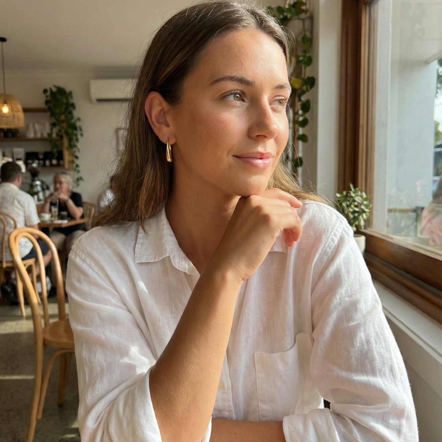 Pair of polished gold tapered raindrop earrings with elongated hook design on white background.
