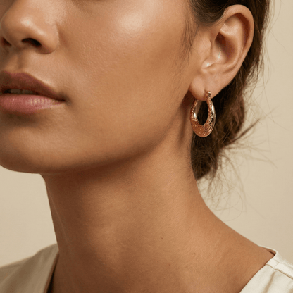 Molten Swirl Gold Hoop Earrings, Close-up of a woman wearing gold hoop earrings against a neutral background