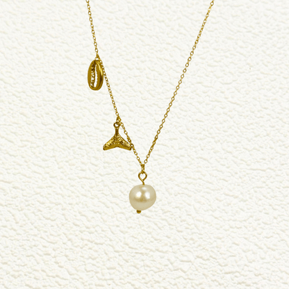 Gold necklace with pearl, whale tail, and shell charms on dainty waterproof chain