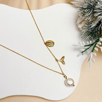 Gold necklace with pearl, whale tail, and shell charms on dainty waterproof chain