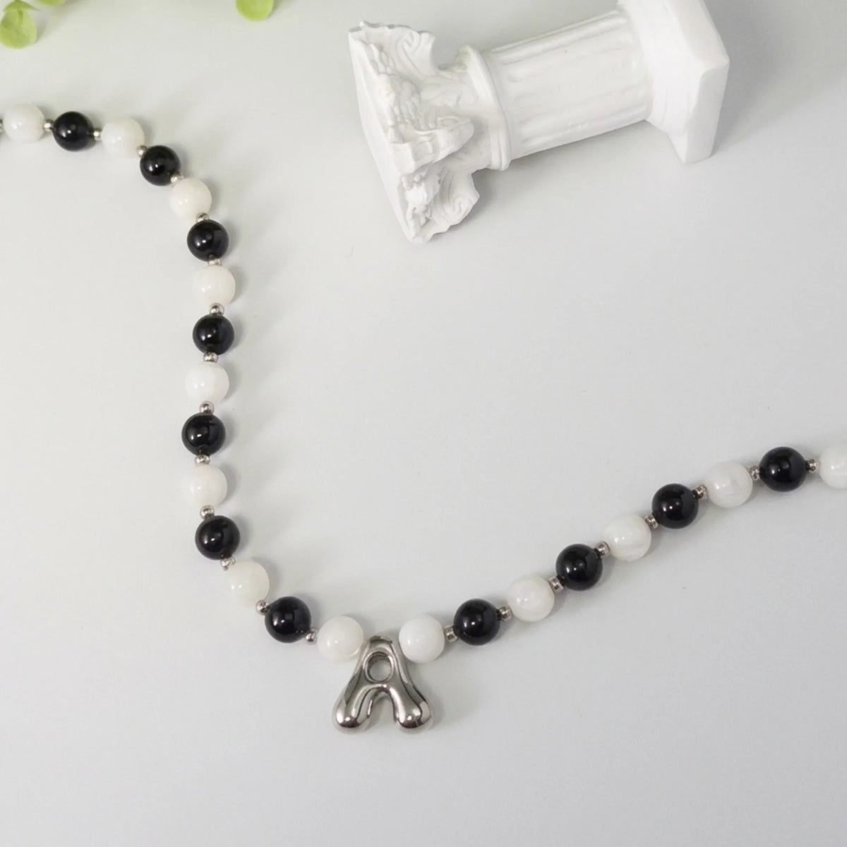 personalised sterling silver necklace with alternating black onyx and white mother-of-pearl bead, gold spacers and bubble initial