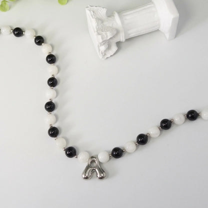 personalised sterling silver necklace with alternating black onyx and white mother-of-pearl bead, gold spacers and bubble initial