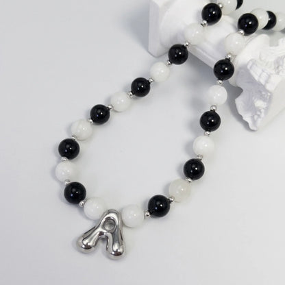 personalised sterling silver necklace with alternating black onyx and white mother-of-pearl bead, gold spacers and bubble initial