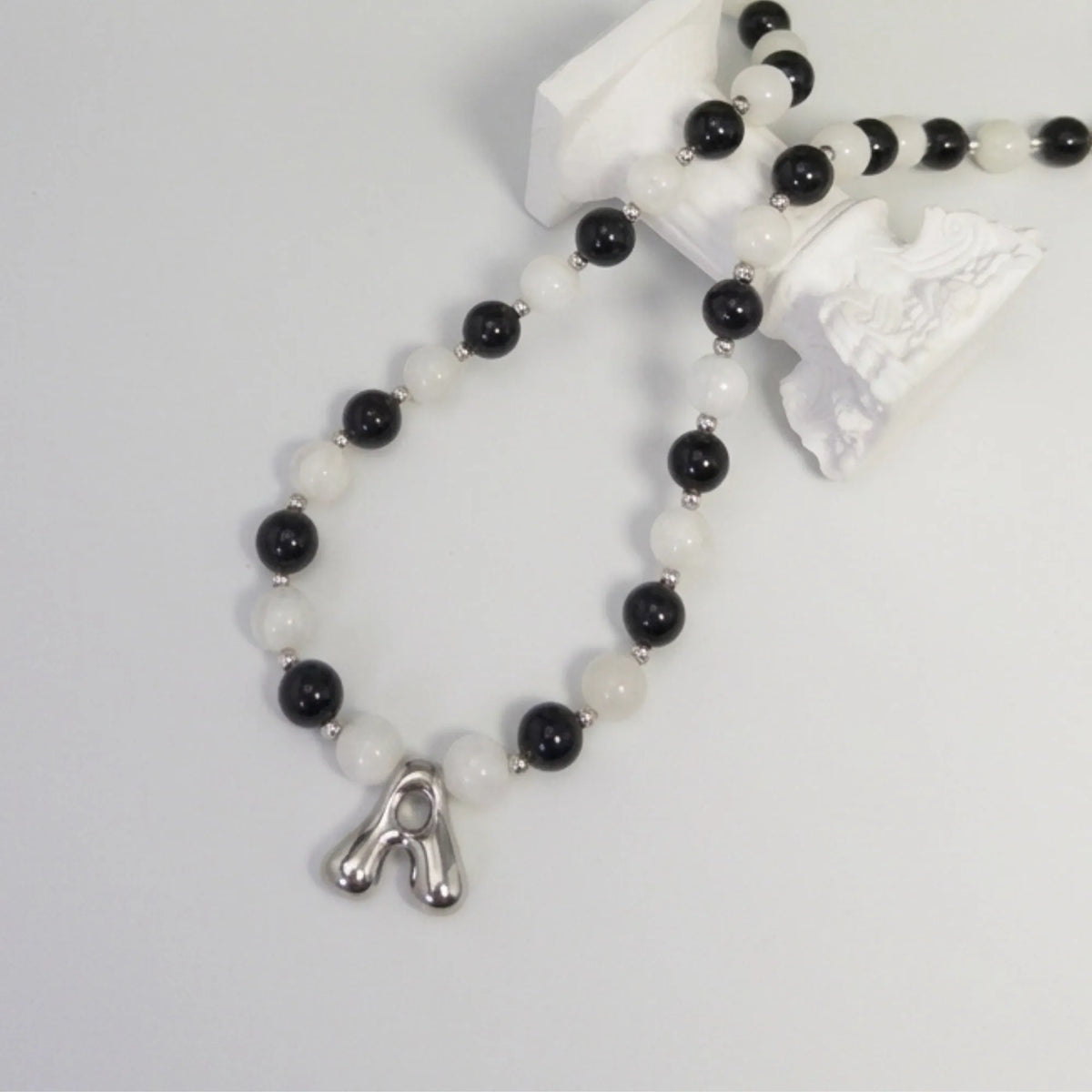 personalised sterling silver necklace with alternating black onyx and white mother-of-pearl bead, gold spacers and bubble initial