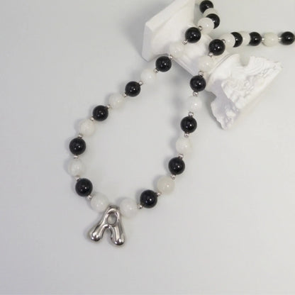 personalised sterling silver necklace with alternating black onyx and white mother-of-pearl bead, gold spacers and bubble initial