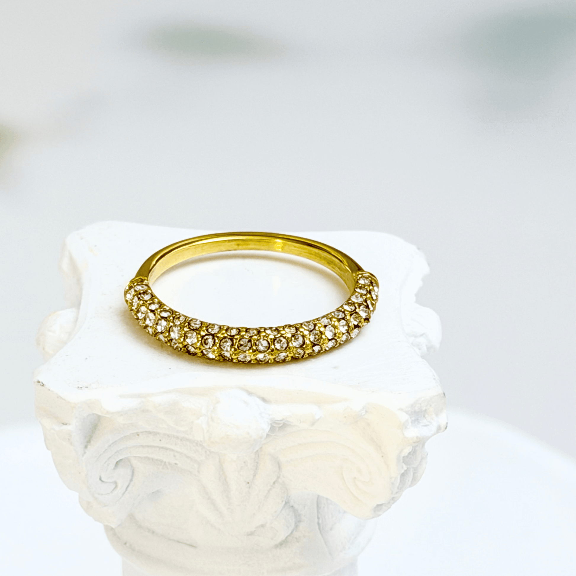 Gold pavé crystal ring on a white display stand — MXW Jewellery product photo.