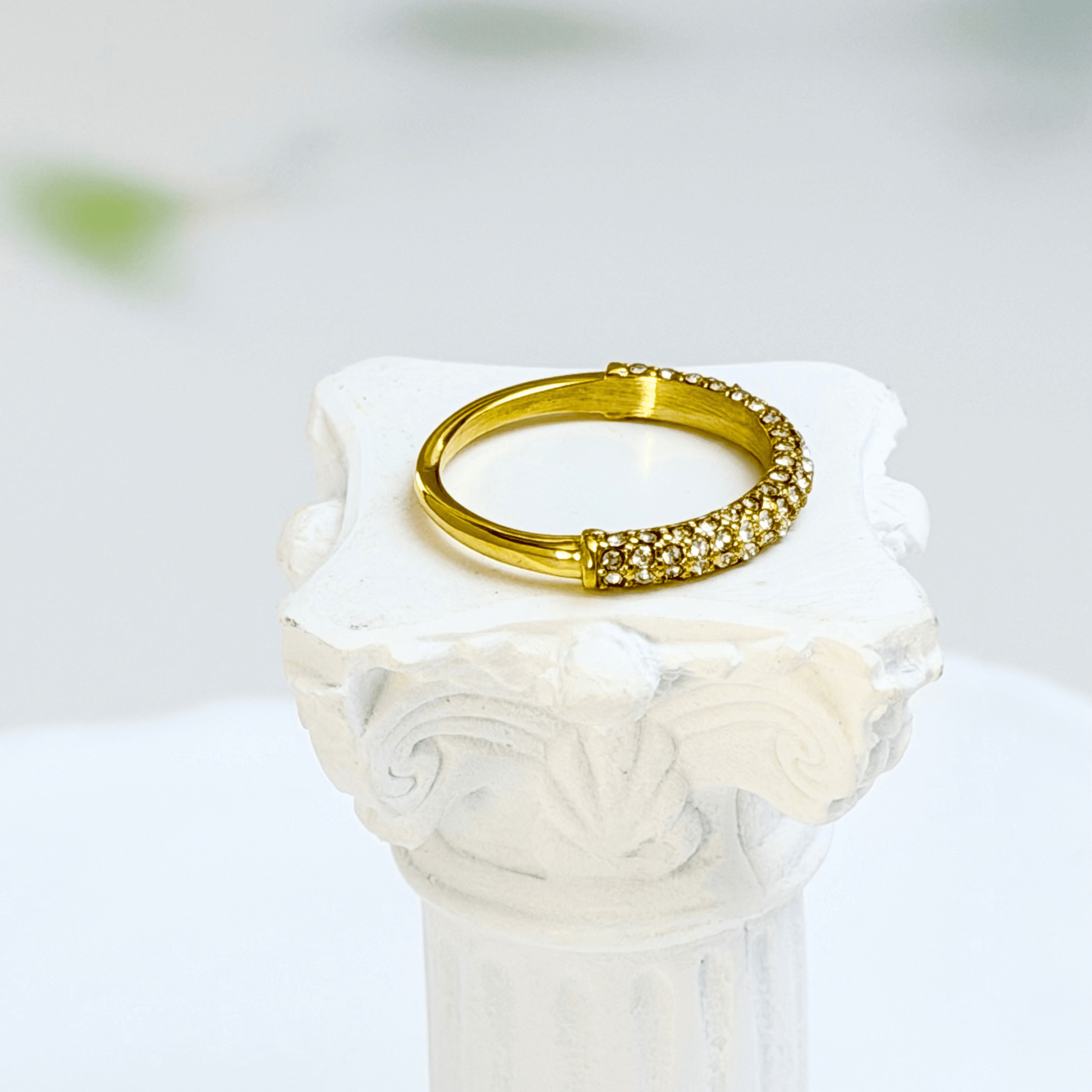 Gold pavé crystal ring on a white display stand — MXW Jewellery product photo.