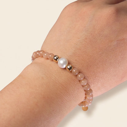 A beaded bracelet featuring peach moonstone beads, premium freshwater pearl, and a stamped initial disc, 14k gold filled. MXW Jewellery