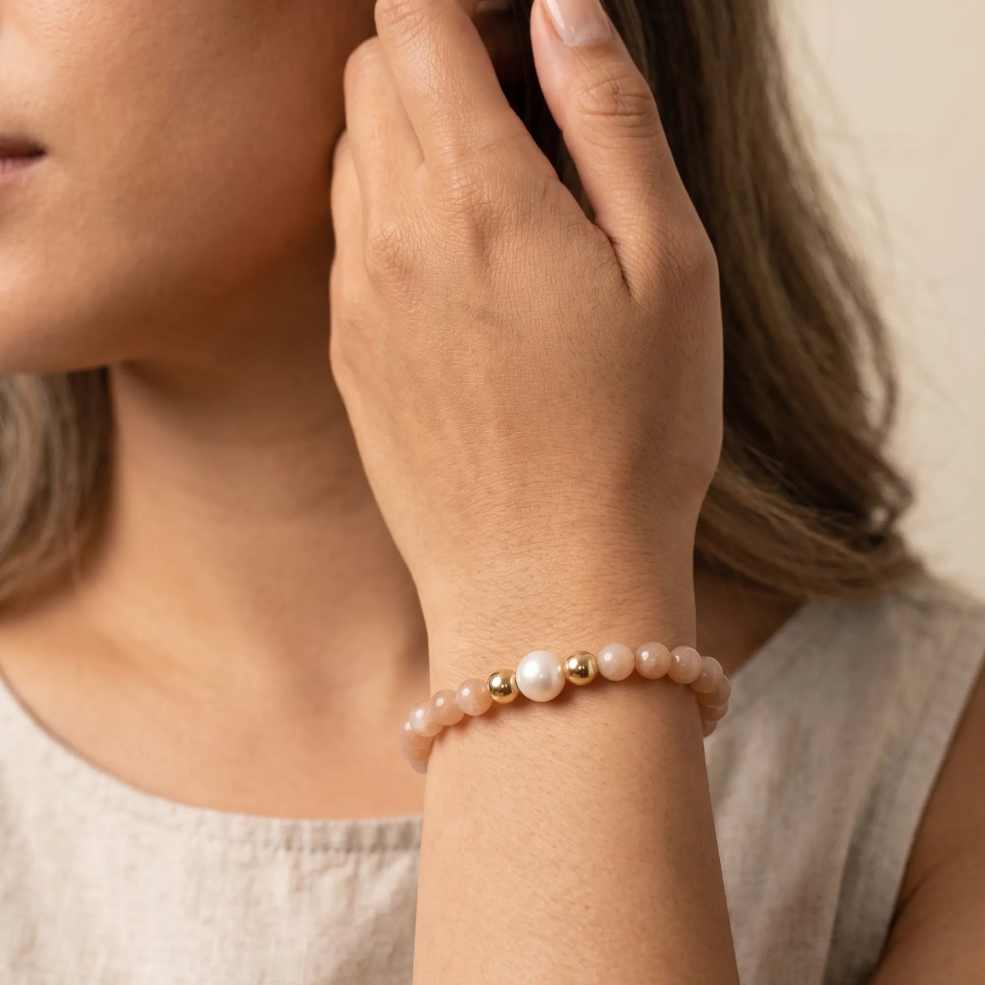 A beaded bracelet featuring peach moonstone beads, premium freshwater pearl, and a stamped initial disc, 14k gold filled. MXW Jewellery