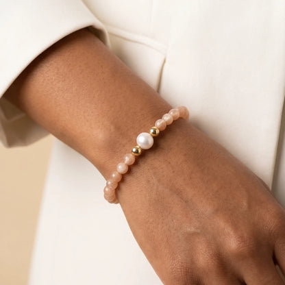 A beaded bracelet featuring peach moonstone beads, premium freshwater pearl, and a stamped initial disc, 14k gold filled. MXW Jewellery