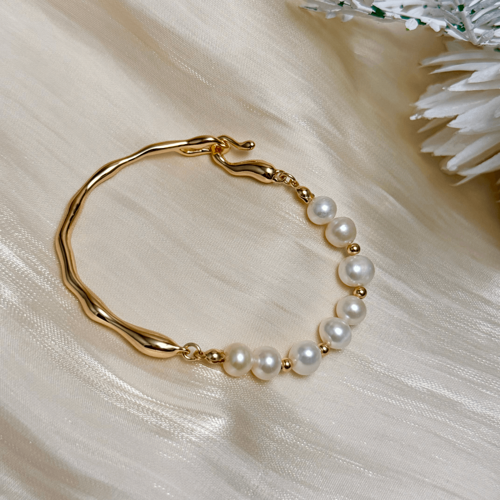 bracelet featuring freshwater pearls and sculptural molten gold band in an open, adjustable design
