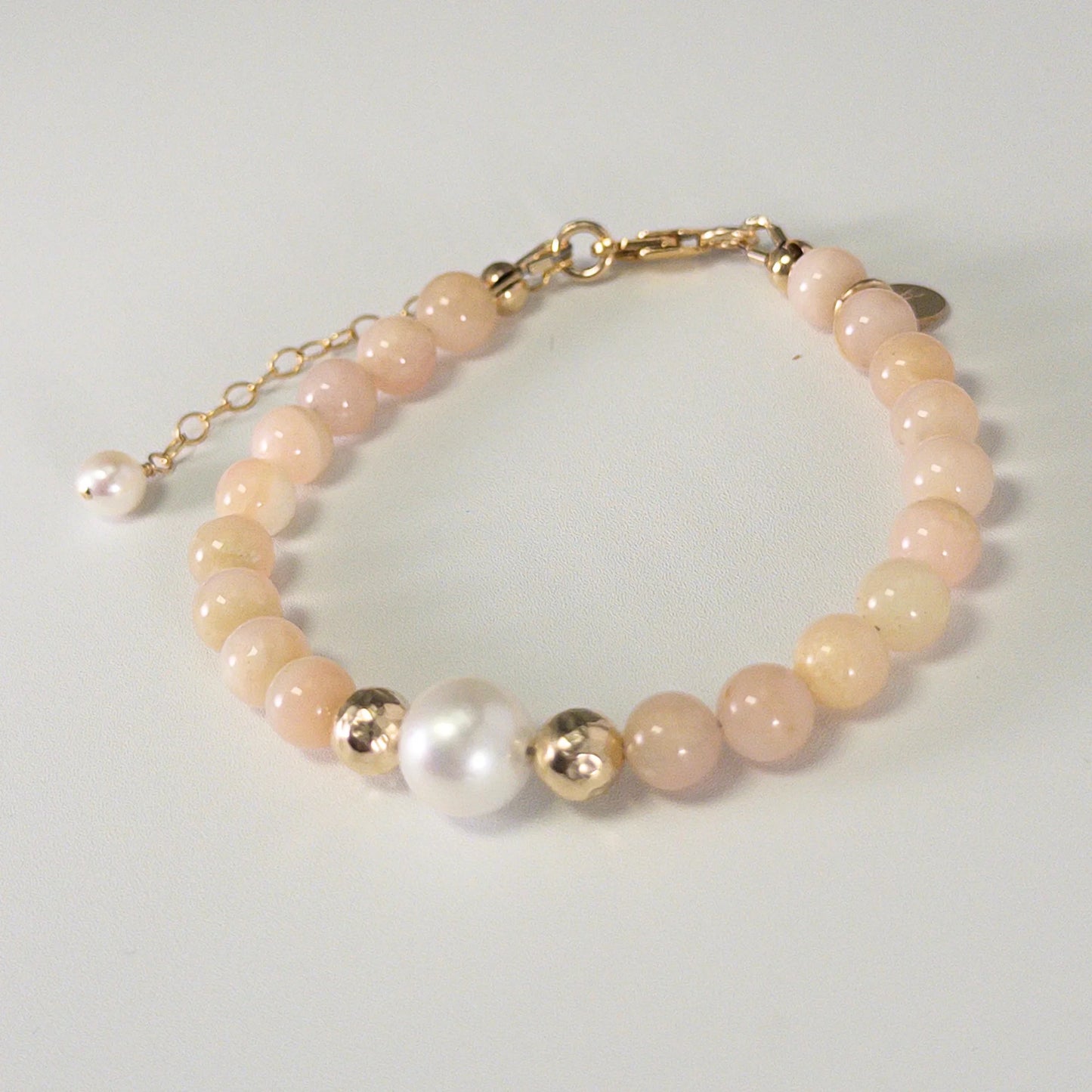 Pink opal, pearl and initial gold bracelet featuring soft pink gemstone beads, lustrous freshwater pearls and a personalised gold-filled stamped initial disc.