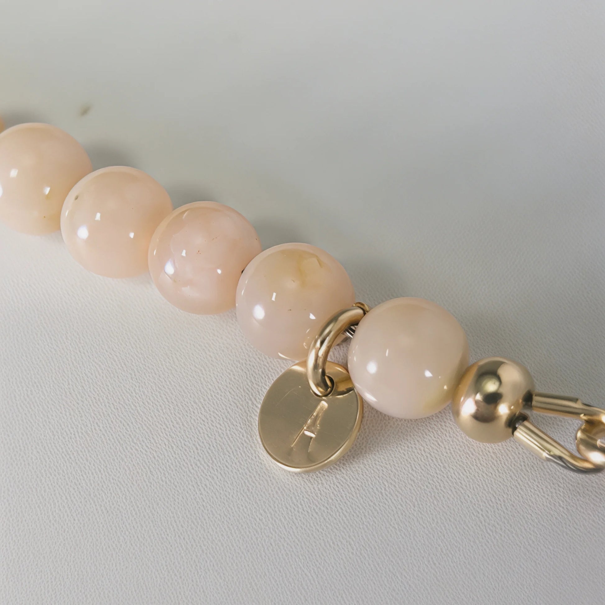 Pink opal, pearl and initial gold bracelet featuring soft pink gemstone beads, lustrous freshwater pearls and a personalised gold-filled stamped initial disc.