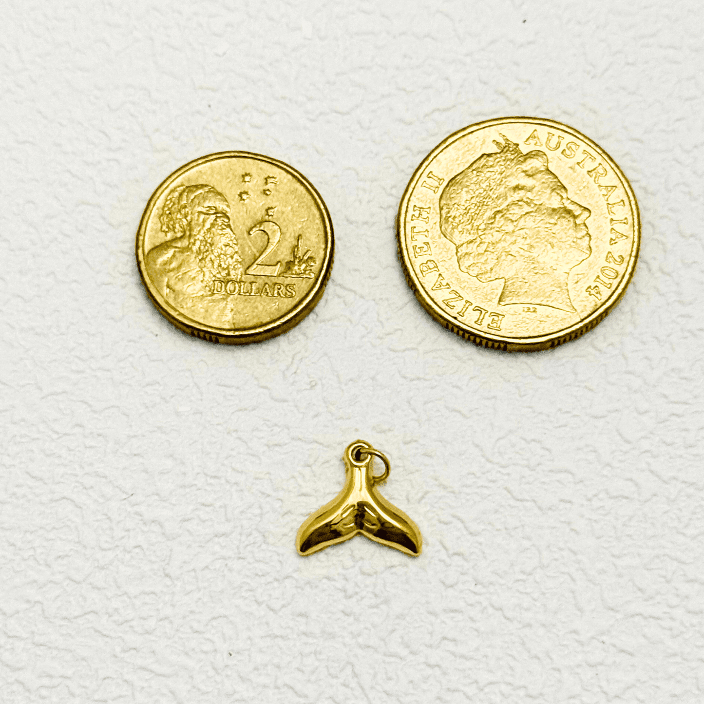 Shiny gold whale tail charm with smooth finish