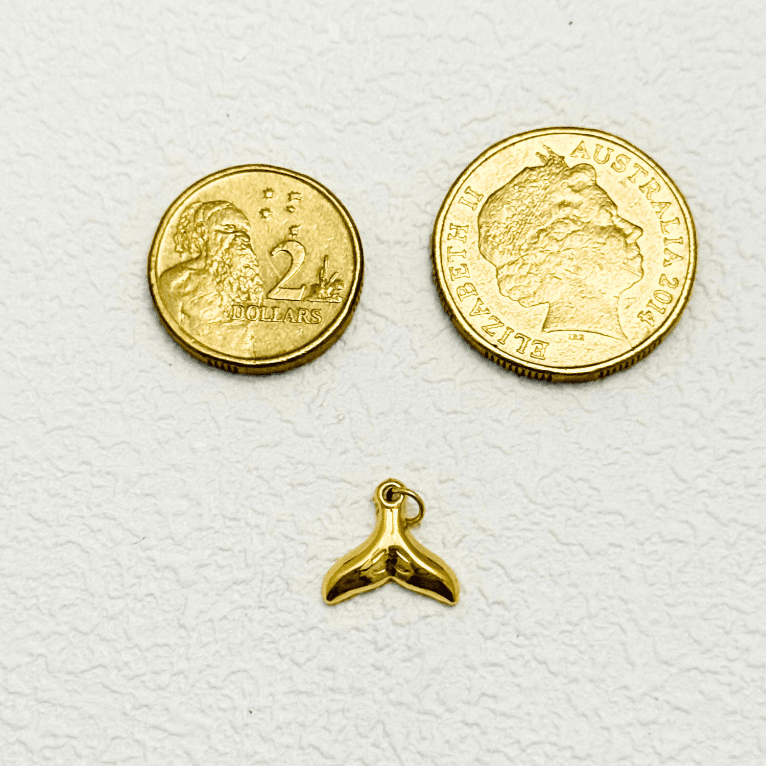 Shiny gold whale tail charm with smooth finish