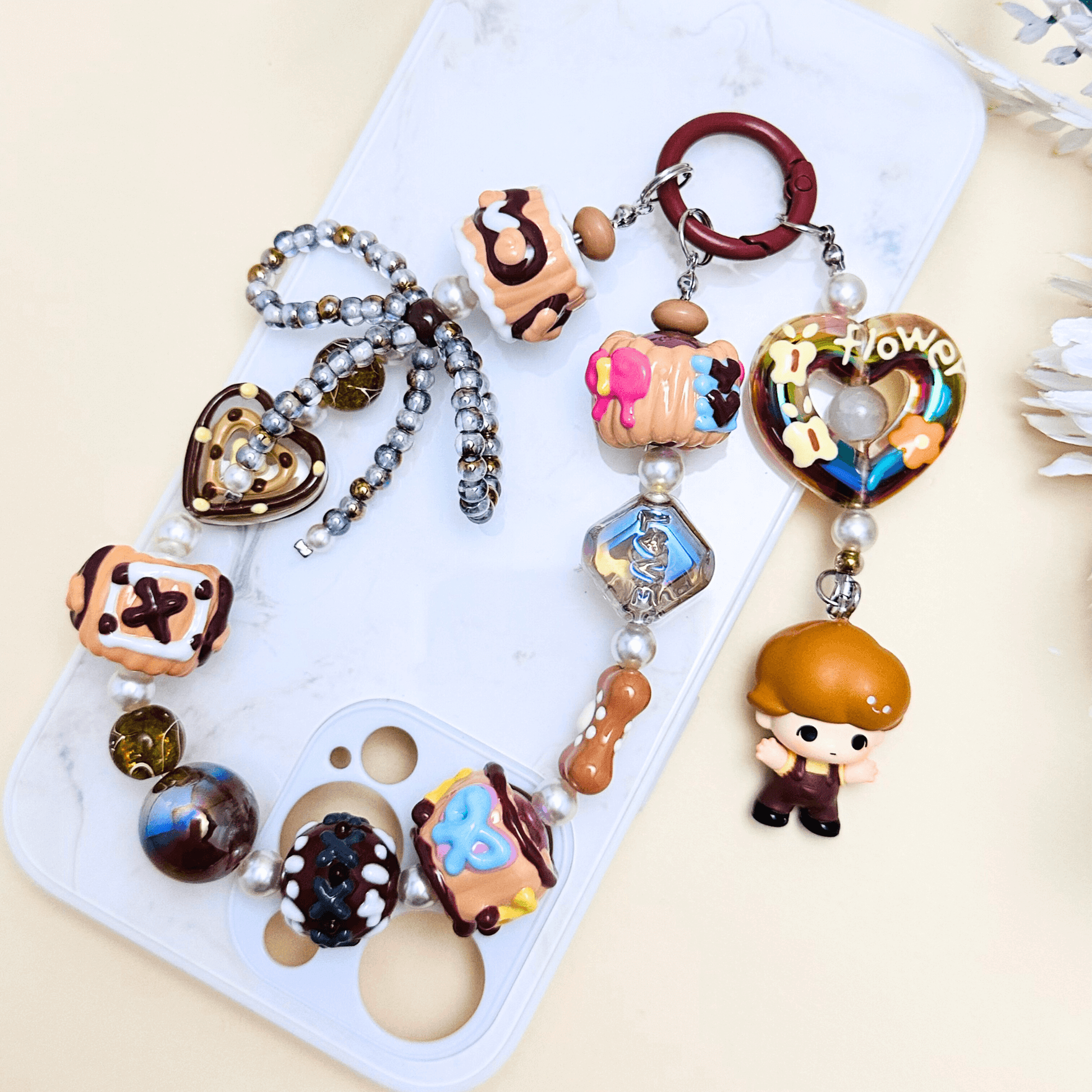 Handmade Pop Bean Brown Dimoo phone charm with hand-painted polymer clay beads and faux pearls, attached to a keychain.