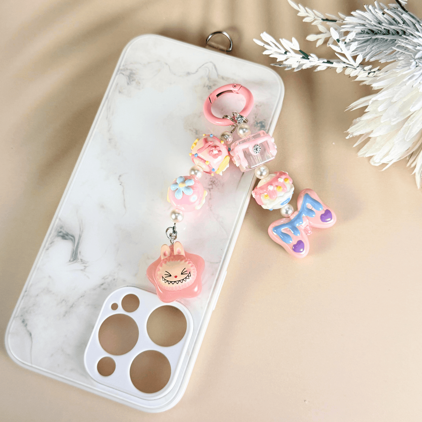 Pop Bean Labubu handmade phone charm in pink star theme, featuring kawaii beads, flowers, and a playful character, attached to a white marble phone case – cute accessory by MXW Jewellery