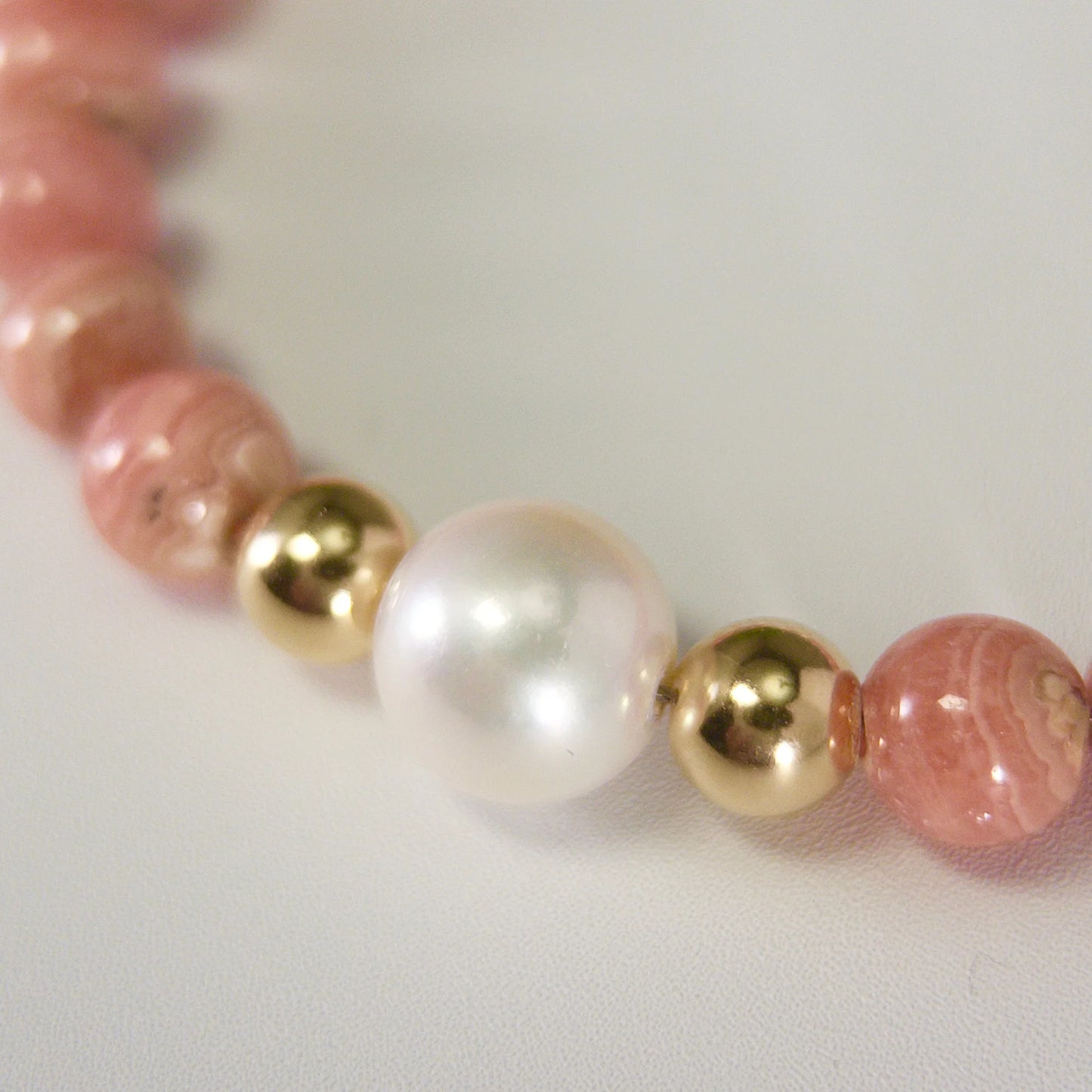 Rhodochrosite, pearl and initial gold bracelet featuring natural pink gemstone beads, lustrous freshwater pearls and a personalised gold-filled stamped initial disc.