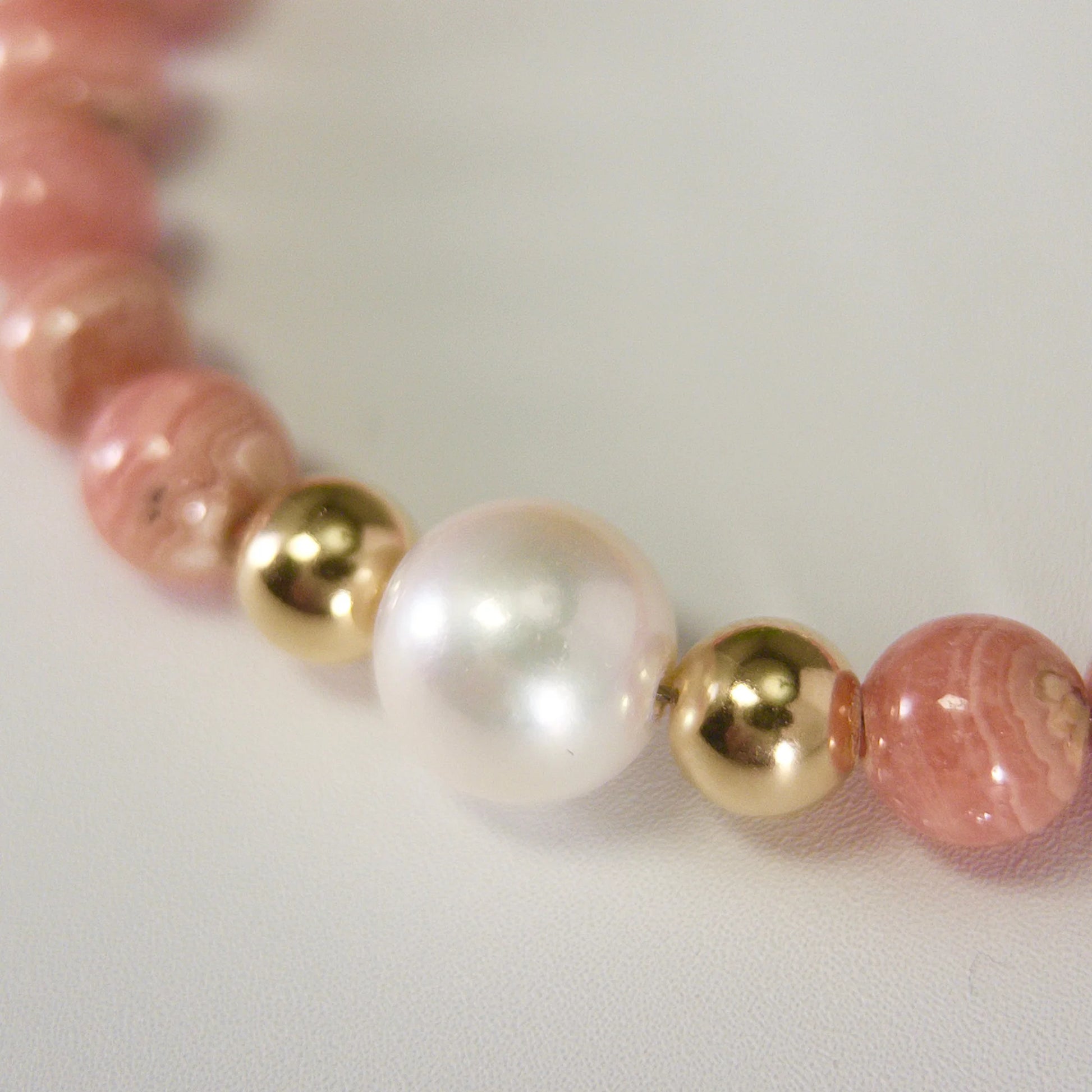 Rhodochrosite, pearl and initial gold bracelet featuring natural pink gemstone beads, lustrous freshwater pearls and a personalised gold-filled stamped initial disc.