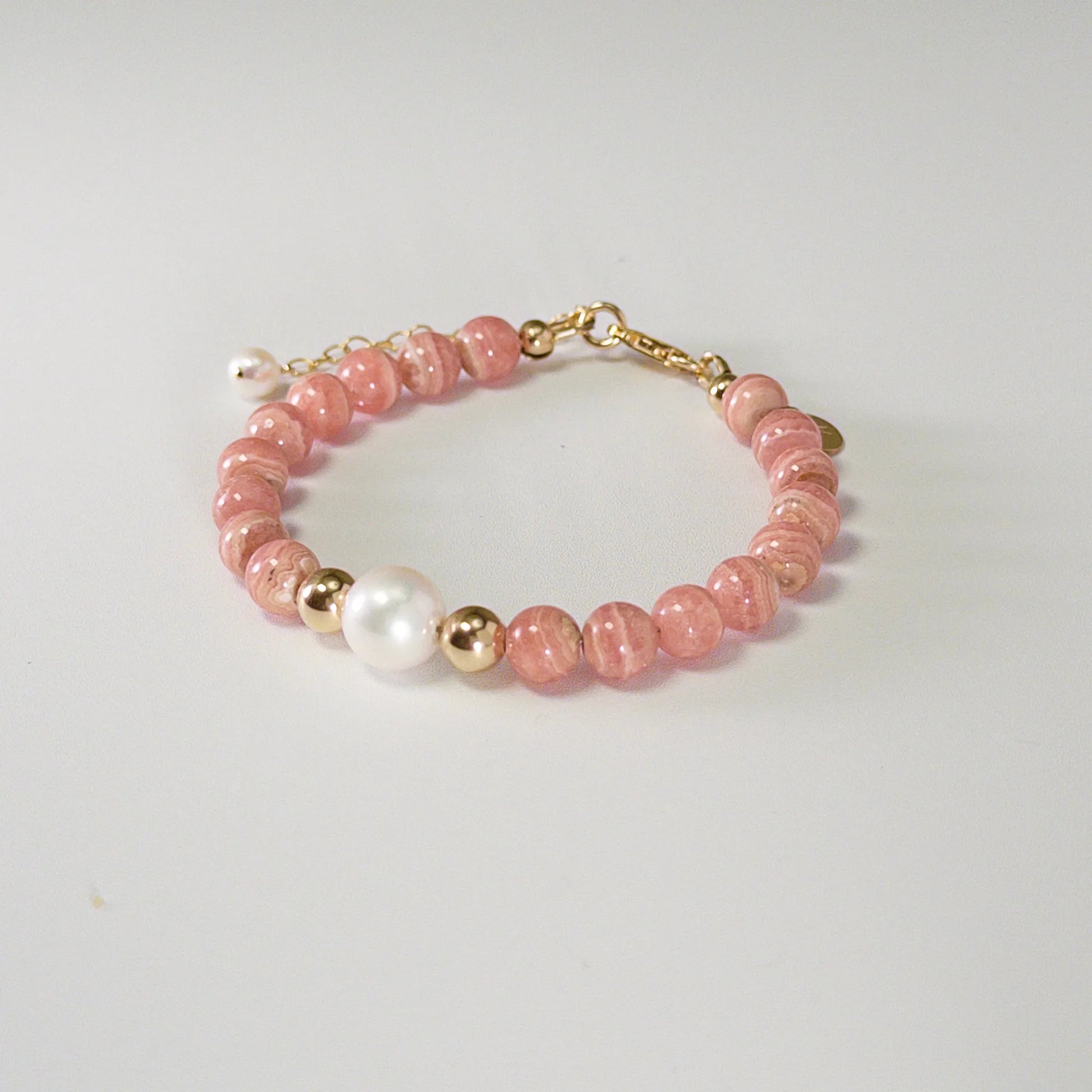 Rhodochrosite, pearl and initial gold bracelet featuring natural pink gemstone beads, lustrous freshwater pearls and a personalised gold-filled stamped initial disc.