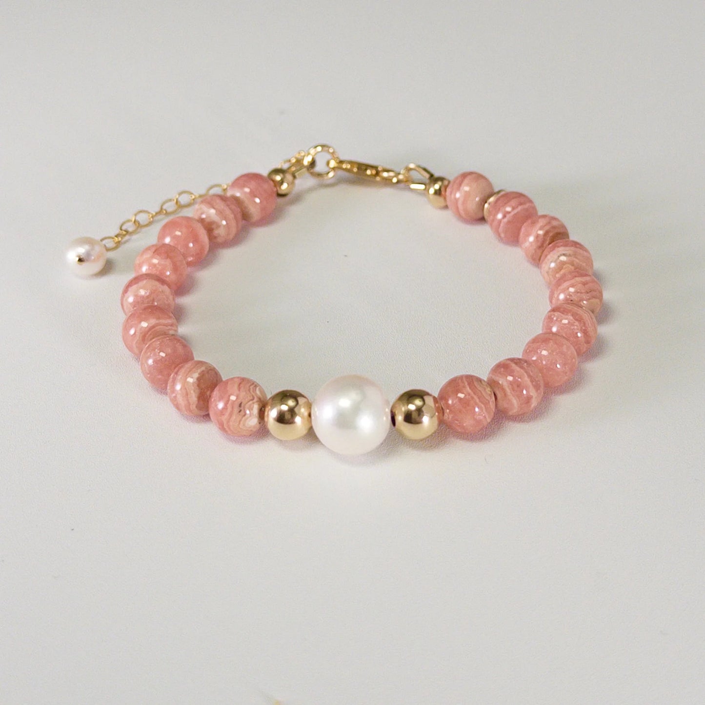 Rhodochrosite, pearl and initial gold bracelet featuring natural pink gemstone beads, lustrous freshwater pearls and a personalised gold-filled stamped initial disc.