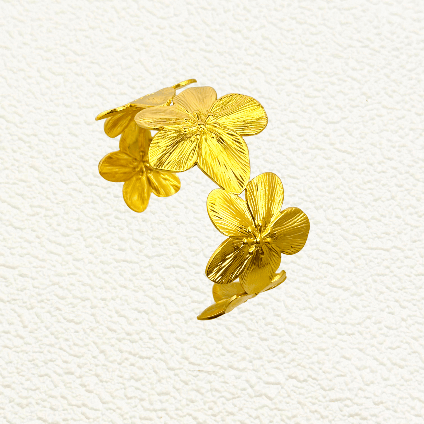 Gold floral open cuff bangle bracelet featuring five sculpted flowers in PVD gold-plated stainless steel – waterproof and tarnish-resistant statement jewellery piece.
