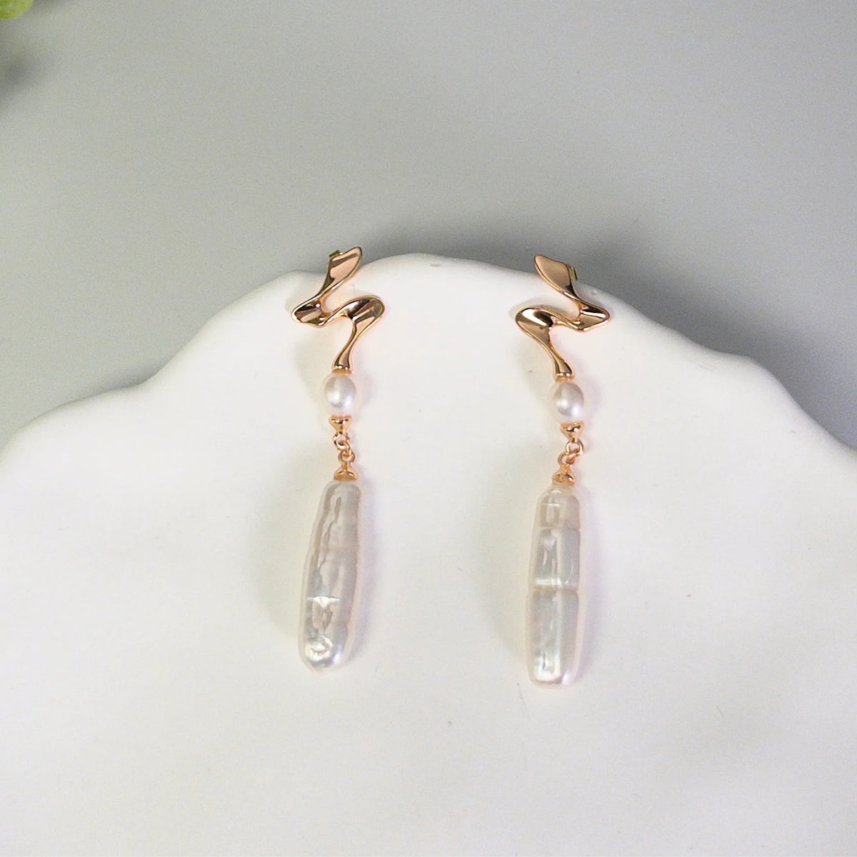 MXW gold vermeil drop earrings with a sculpted wave stud, a round freshwater pearl and a long baroque pearl drop.