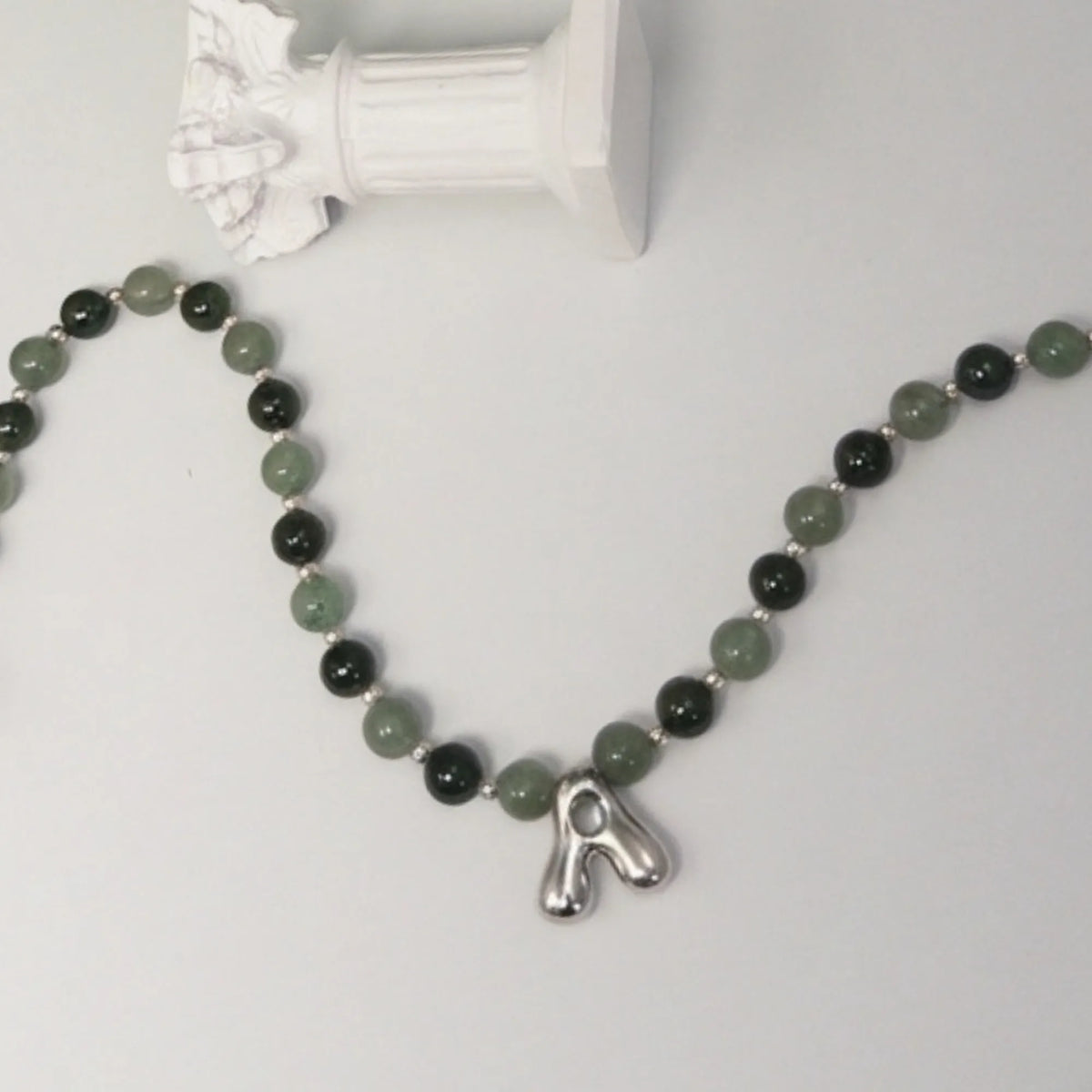 sterling silver necklace with alternating nephrite jade and green aventurine beads and a bubble letter pendant.