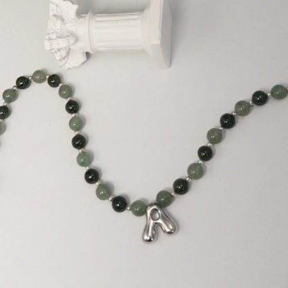 sterling silver necklace with alternating nephrite jade and green aventurine beads and a bubble letter pendant.
