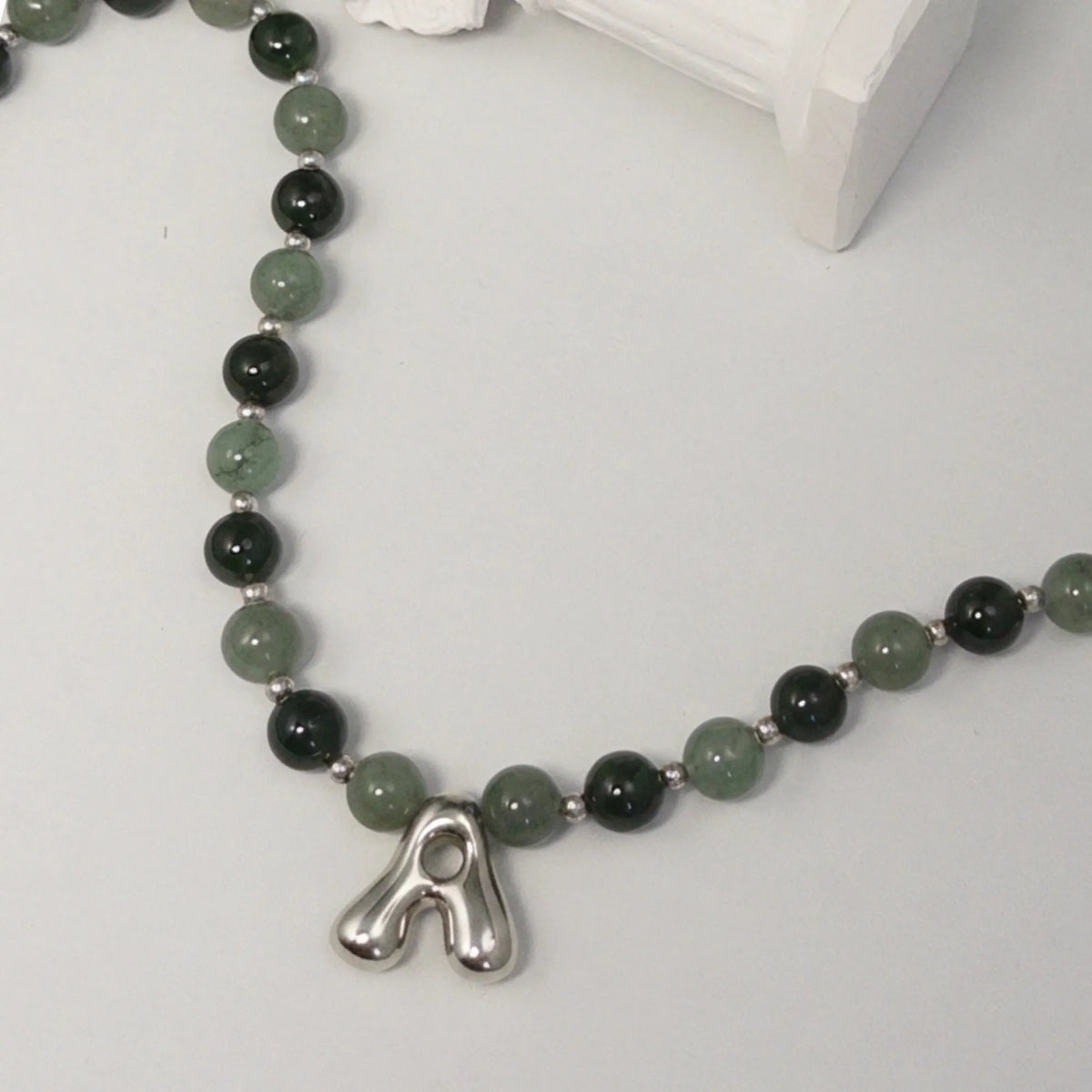 sterling silver necklace with alternating nephrite jade and green aventurine beads and a bubble letter pendant.