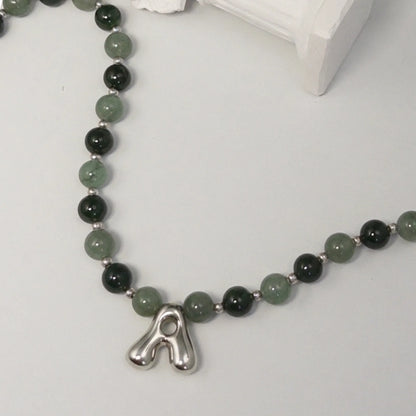 sterling silver necklace with alternating nephrite jade and green aventurine beads and a bubble letter pendant.