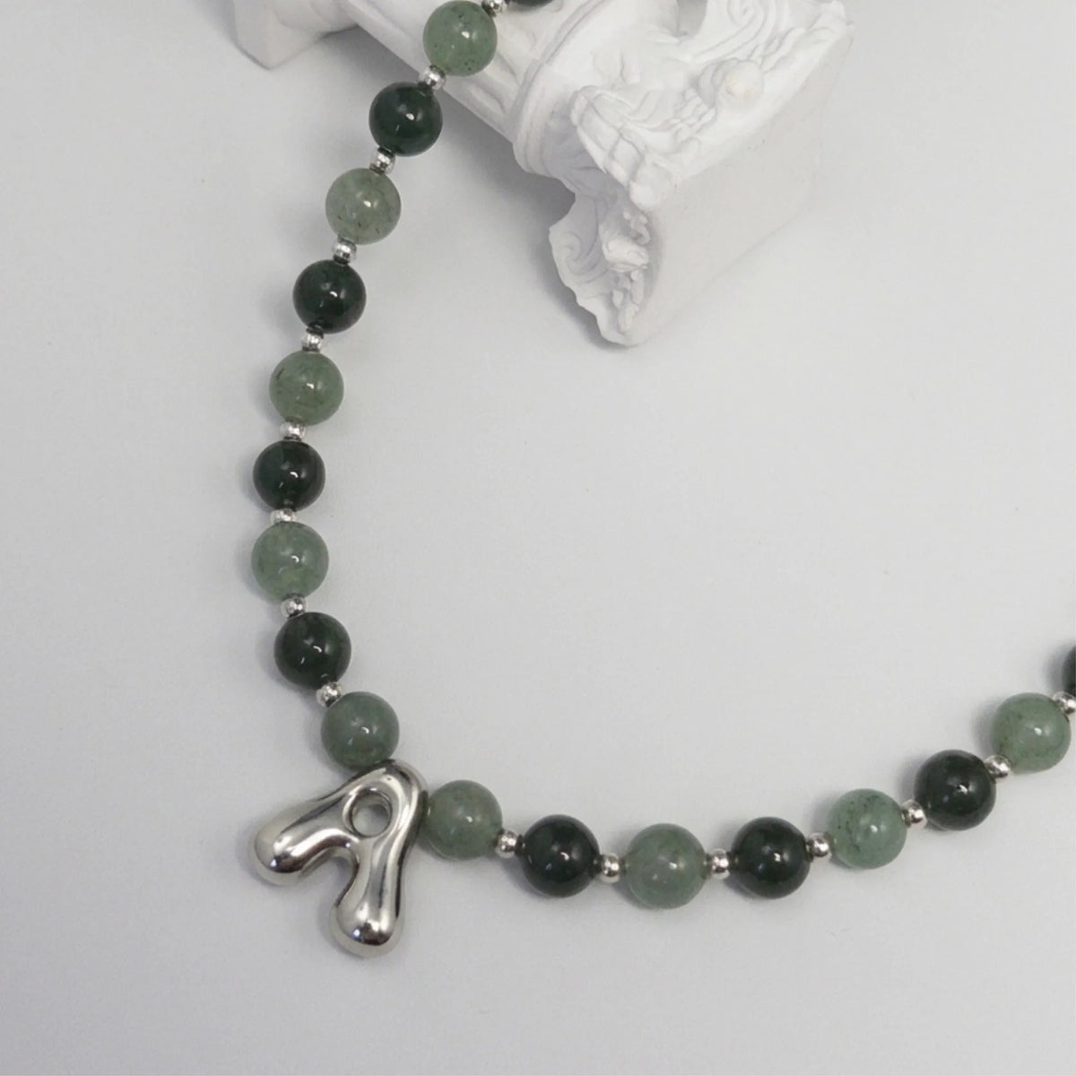 sterling silver necklace with alternating nephrite jade and green aventurine beads and a bubble letter pendant.