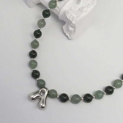 sterling silver necklace with alternating nephrite jade and green aventurine beads and a bubble letter pendant.