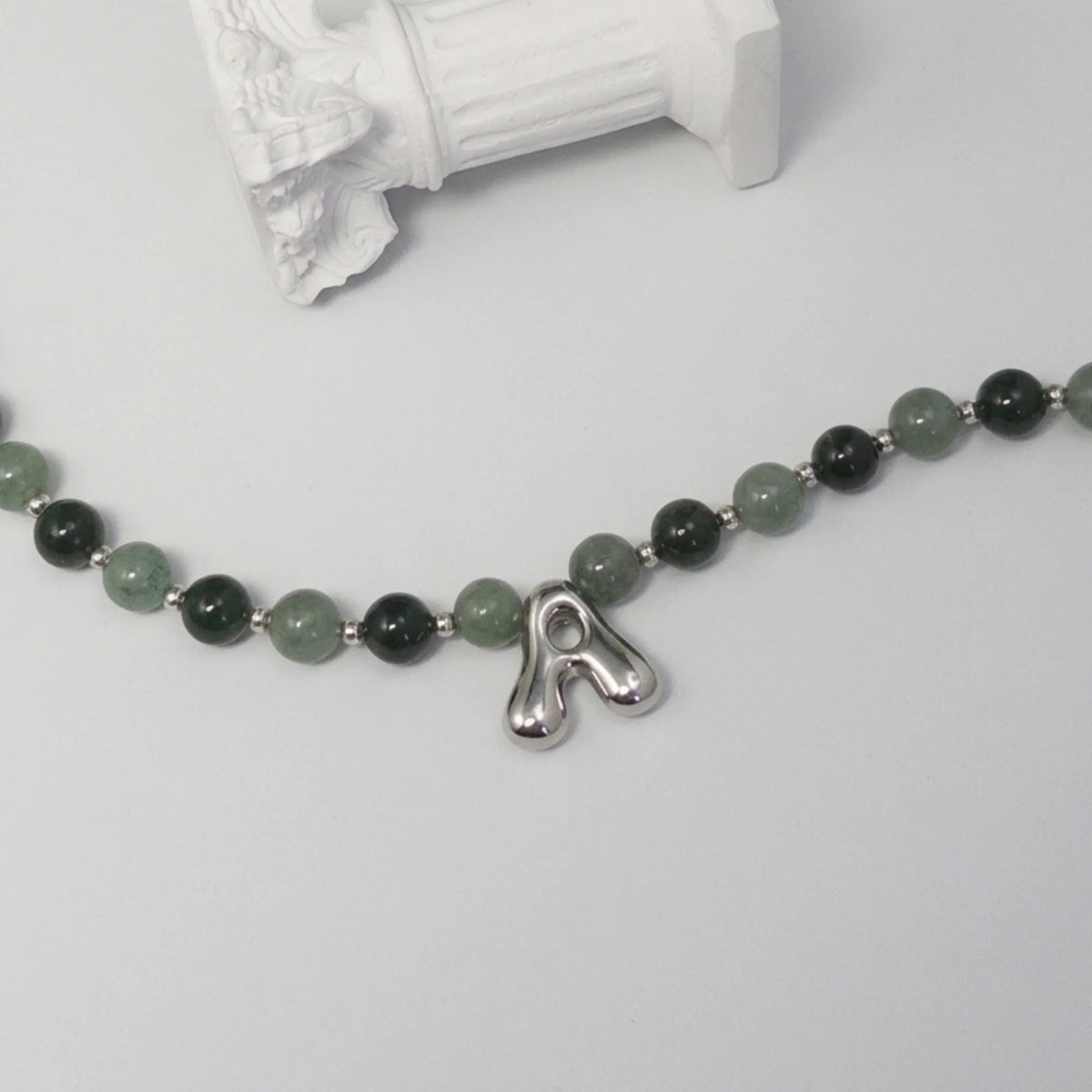 sterling silver necklace with alternating nephrite jade and green aventurine beads and a bubble letter pendant.