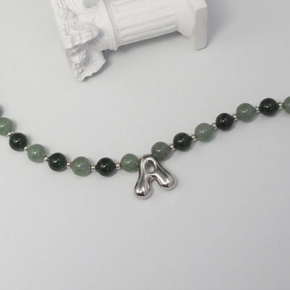 sterling silver necklace with alternating nephrite jade and green aventurine beads and a bubble letter pendant.