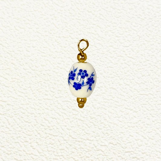 Small oval ceramic charm with delicate blue blossom design and gold beads