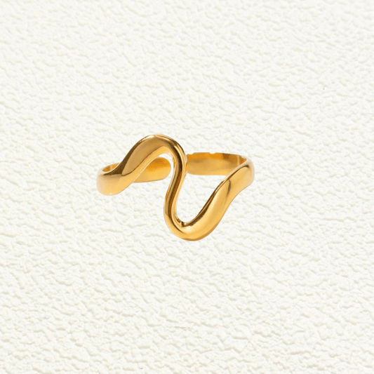 Gold minimalist open ring with soft wave-shaped design on white ceramic background.