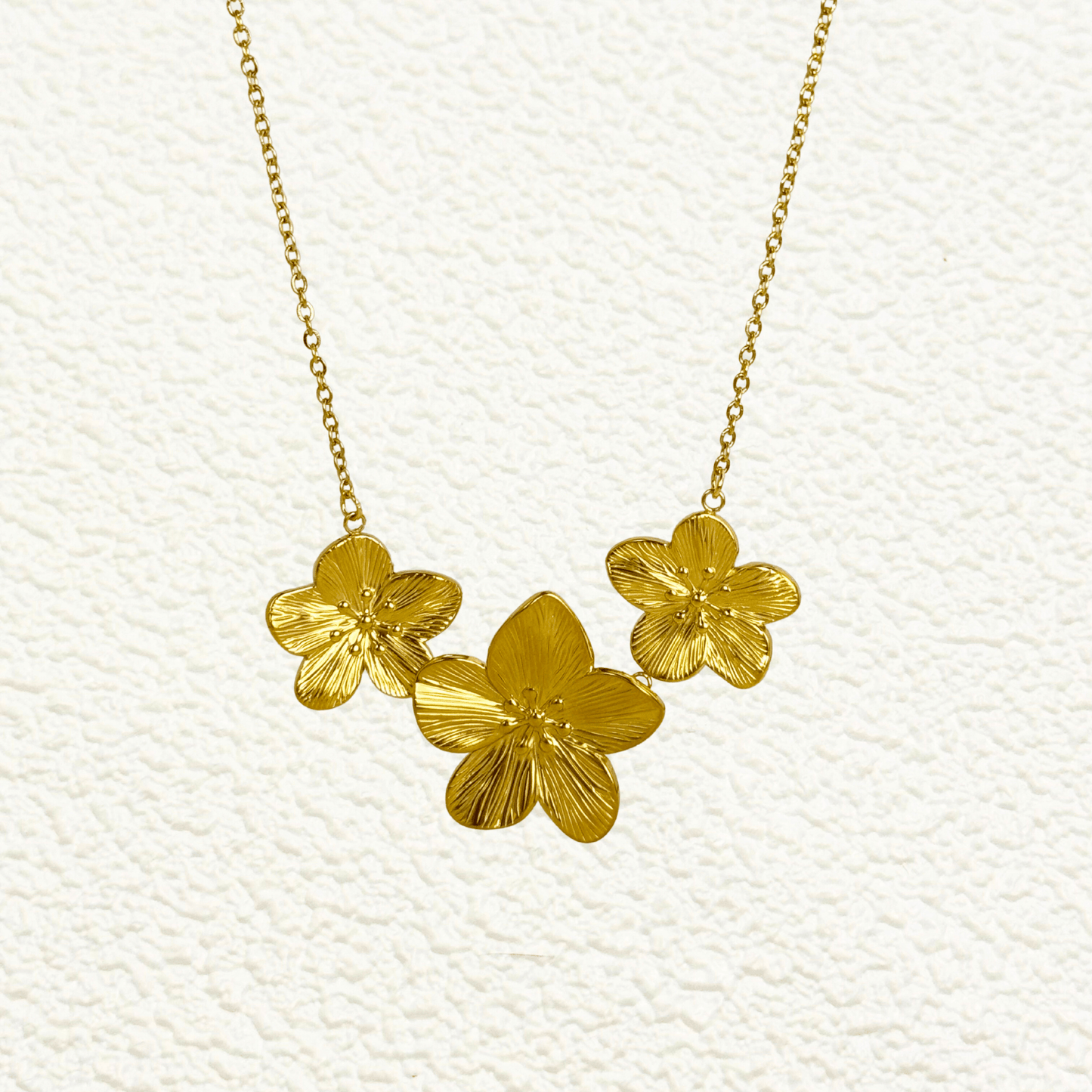 Gold triple flower pendant necklace with detailed floral design, made from waterproof PVD gold-plated stainless steel, displayed on a neutral background.